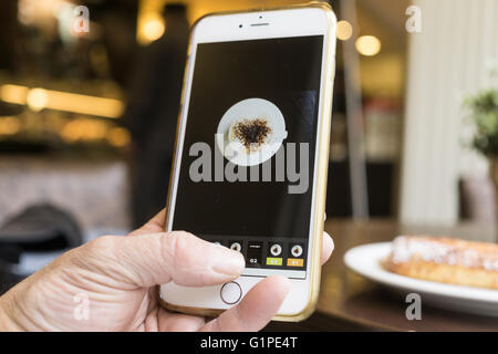 Berlino, Germania - 17 Maggio 2016: l'uomo modifica la sua foto mobile di una tazza di caffè con iPhone e camma VSCO app. Foto Stock