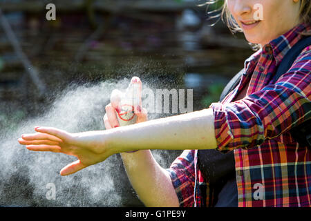 Un repellente per le zanzare, giovane donna usa un repellente spray, prima di una escursione, mediante spruzzatura sulla pelle, Foto Stock