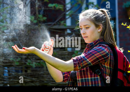 Un repellente per le zanzare, giovane donna usa un repellente spray, prima di una escursione, mediante spruzzatura sulla pelle, Foto Stock