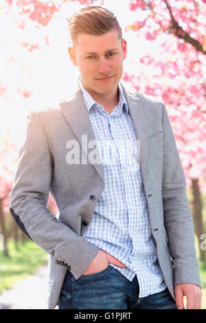 Ritratto di uomo bello nella parte anteriore del fiore di ciliegio Foto Stock