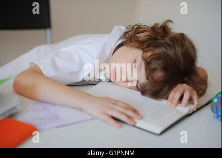 Il ragazzo si è addormentato in classe seduti su un banco di scuola Foto Stock