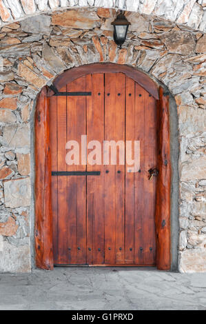 Arcuata di porta di legno in una parete di pietra Foto Stock