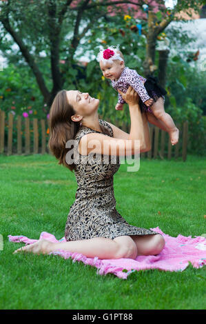 Il bambino e il concetto di paternità - happy madre con bambino seduto su una coperta in posizione di parcheggio Foto Stock