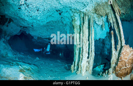 Subacqueo nuotando attraverso formazioni calcaree di un messicano cenote. Foto Stock