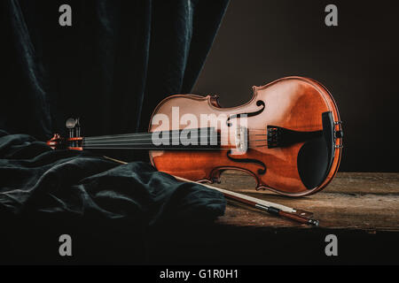 Vecchio violino su una tavola in legno rustico con arco e telo still life, arti e il concetto di musica Foto Stock