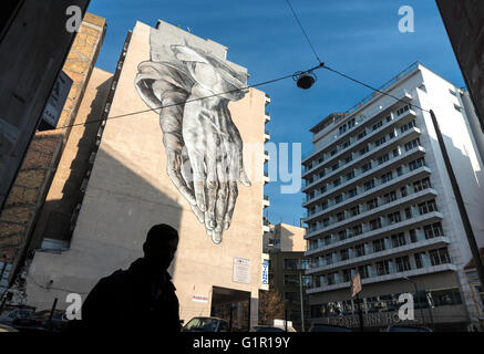 Un arte di strada murale in forma di un gigante di coppia di pregare telai a mano sulla Pireos street nel quartiere di Omonia di Atene, Grecia Foto Stock