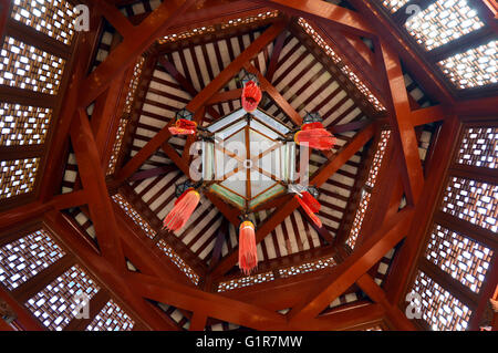 Modello geometrico di travi di legno in un gazebo cinese soffitto con lanterne pensili Foto Stock