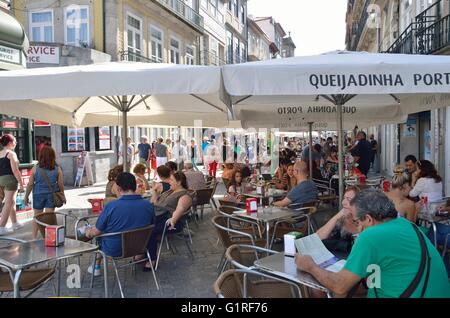 Persone mangiare all'aperto in una strada animata nel centro storico di Porto, Portogallo. Foto Stock