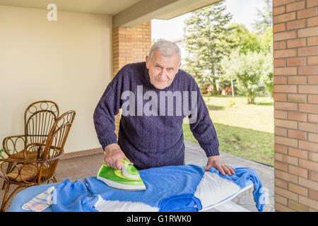 La stiratura Senior nel patio della sua casa Foto Stock