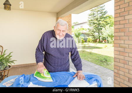 La stiratura Senior nel patio della sua casa Foto Stock