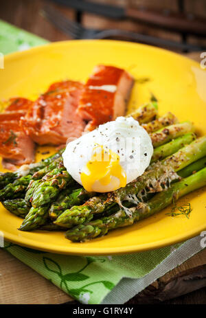 Deliziosi arrosti di asparagi verdi, uovo in camicia e salmone affumicato su piastra Foto Stock