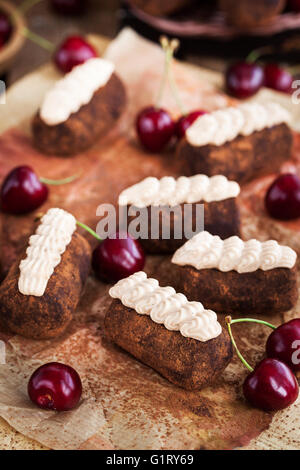 Il rum cioccolato sfere torte decorate con panna e ciliegie fresche Foto Stock