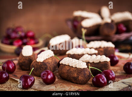 Il rum cioccolato sfere torte decorate con panna e ciliegie fresche Foto Stock