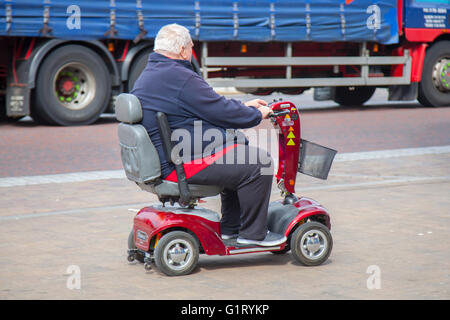 Senior, sovrappeso. La persona con disabilità pensionato che utilizza lo scooter Powered Mobility in movimento sul lungomare di Blackpool, Lancashire, Regno Unito Foto Stock