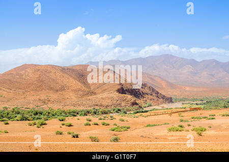 Strada solitaria passa vicino alle montagne nel deserto del Marocco Foto Stock