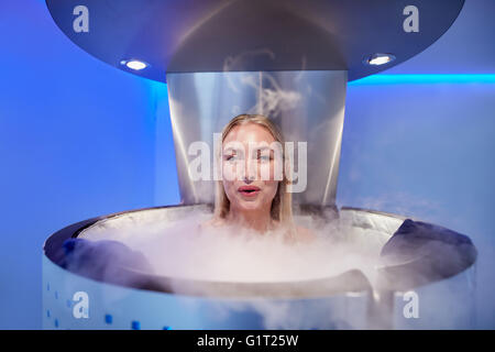 Ritratto di felice giovane donna in un intero corpo crioterapia cabina. Guarda la fotocamera e sorridente. Foto Stock