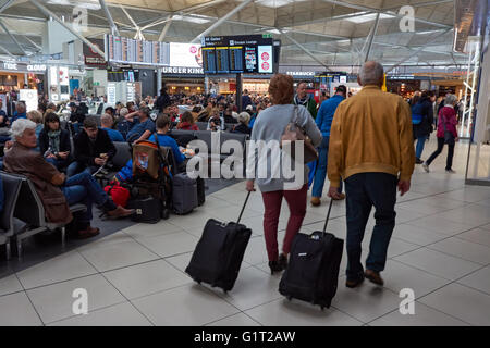 I passeggeri in attesa nella lounge delle partenze presso l'aeroporto Stansted di Londra, Inghilterra, Regno Unito Foto Stock