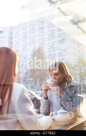 Le donne bere il tè al cafè sul marciapiede Foto Stock