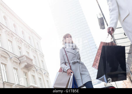 Le donne con le borse per lo shopping della città di attraversamento strada sotto il grattacielo Foto Stock