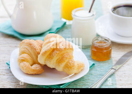 Romantica colazione tropicale cornetti, caffè, succo di frutta e miele e yogurt Foto Stock