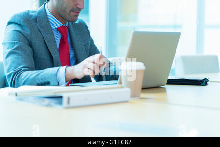 Imprenditore focalizzato lavora al computer portatile in sala conferenze Foto Stock