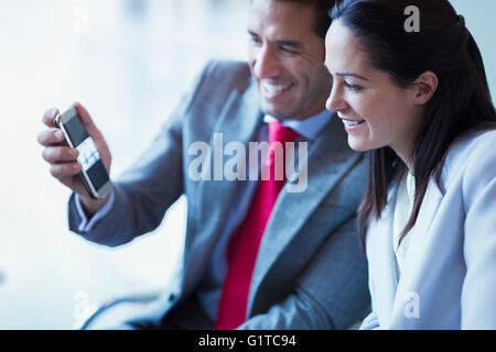 Imprenditore mostra telefono cellulare video di imprenditrice Foto Stock