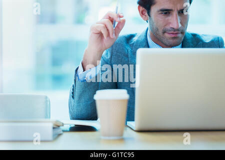 Imprenditore focalizzato lavora al computer portatile in ufficio Foto Stock