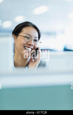 Sorridente imprenditrice parlando al telefono in ufficio Foto Stock