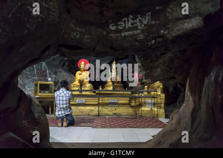 L'uomo prega all'interno della caverna, Bayint Nyi (Bayin Gyi Gu o Begyinni) tempio nella grotta, Stato Mon, Birmania (Myanmar) Foto Stock