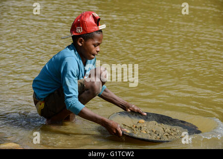 MADAGASCAR, regione Manajary, città Vohilava, piccola scala miniere d'oro, i bambini il panning per oro a fiume ANDRANGARANGA / Madagascar Mananjary, Vohilava, kleingewerblicher Goldabbau, Kinder waschen Gold am Fluss ANDRANGARANGA, Junge CLEMENCE 12 Jahre Foto Stock