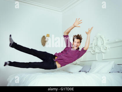Ritratto giocoso uomo saltando sul letto Foto Stock