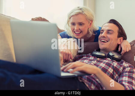 Coppia sorridente utilizzando computer portatile sul divano Foto Stock