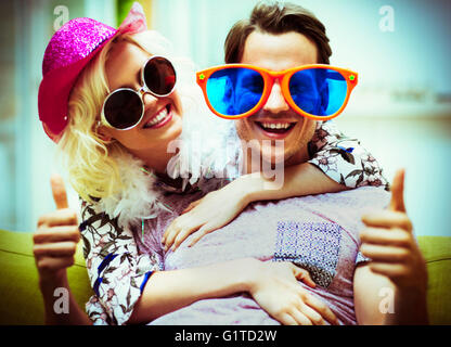 Ritratto di giovane giocoso costume da indossare occhiali da sole e cappello gesticolando pollice in su Foto Stock