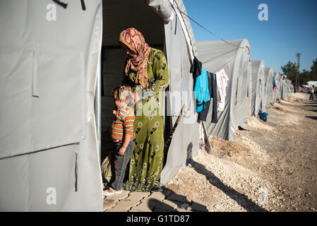 Un rifugiato curdo donna da Kobani, detiene la figlia in un campo di rifugiati nella città turca di Suruc, vicino al confine Turkish-Syrian. Migliaia di curdi che erano stati costretti ad abbandonare la città siriana di Kobani, che è sotto assedio da parte di uno Stato islamico forze. La maggior parte di loro vivono in campi per rifugiati nella città turca di Suruc. Foto Stock