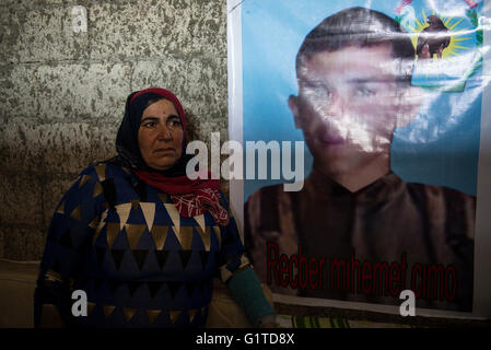 Una donna curda sorge accanto alla foto di suo figlio, chi combatte a città siriane di Kobani, contro lo Stato islamico forze, in un campo di rifugiati nella città turca di Suruc, vicino al confine Turkish-Syrian. Migliaia di curdi che erano stati costretti ad abbandonare la città siriana di Kobani, che è sotto assedio da parte di uno Stato islamico forze. La maggior parte di loro vivono in campi per rifugiati nella città turca di Suruc. Foto Stock