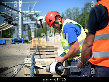 Lavoratori impiombare il filo di controllo per il cavo auto presso il cantiere per la International Garden Show (IGA) di Berlino, Germania, 18 maggio 2916. Molla di avviamento 2017, gondole di cavalcare lungo la 1.5km-lungo percorso ad una altezza di 30 metri. Foto: Britta Pedersen/dpa Foto Stock