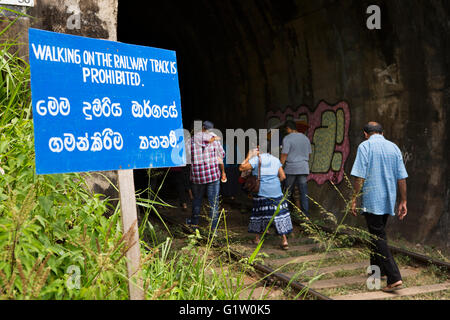 Sri Lanka, Ella, Demodara, persone ignorando il simbolo di sicurezza, camminando attraverso il tunnel Foto Stock