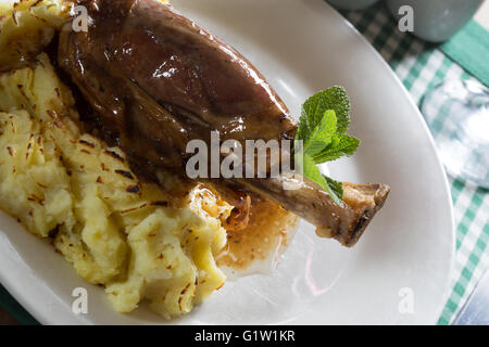 Una porzione di gambo di agnello con salsa alla menta e purea di patate. Foto Stock