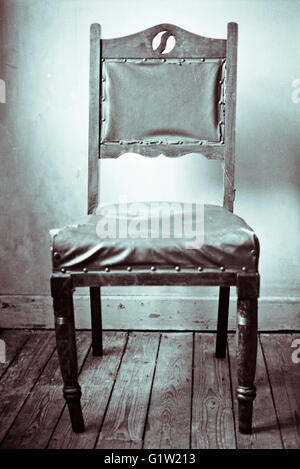 Fotografia in bianco e nero di un vecchio sgangherato stile vittoriano sedia su assi di legno, girato su pellicola Foto Stock