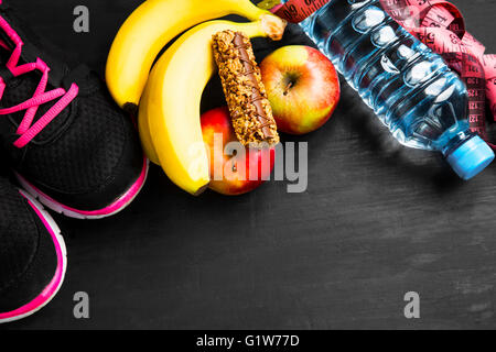 Heathy lifestyle con scarpe da ginnastica, frutta, cereali, bar, bottiglia d'acqua Foto Stock