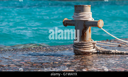 Rusty bollard ormeggio con nave funi e chiaro mare turquouse ocen acqua sullo sfondo Foto Stock