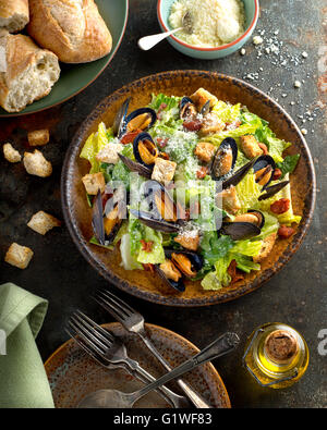 Una deliziosa insalata caesar con cozze, lattuga romana, pancetta, crostini e formaggio parmigiano. Foto Stock