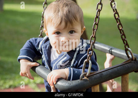 Ritratto di bella un anno vecchio baby ragazza seduta sulle altalene al parco giochi Foto Stock