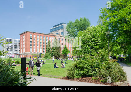 Gli studenti seduti al sole su spazi verdi aperti a Birmingham University campus Foto Stock