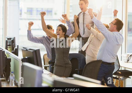 Esuberante la gente di affari il tifo con le braccia sollevate in office Foto Stock