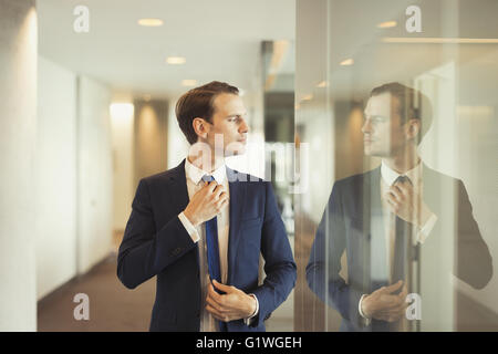 Fiducioso imprenditore tirante di regolazione nel corridoio di office Foto Stock