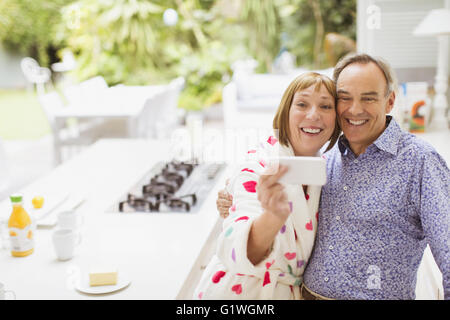 Sorridente Coppia matura tenendo selfie in cucina Foto Stock