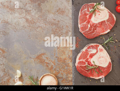 Stinco di vitello per osso Bucco. Carne cruda con erbe e il pepe nero macinato pronti per la cottura Foto Stock