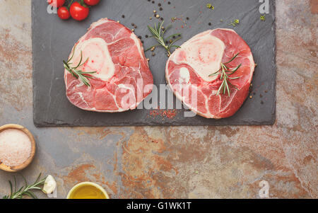 Materie bovine knuckles. Appena il vitello knuckles sulla pietra ardesia e condimenti per la produzione di Osso Buco. Foto Stock