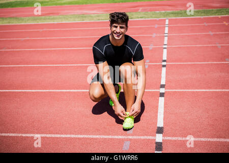 Ritratto di atleta maschio la sua legatura lacci della scarpa sulla via di corsa Foto Stock